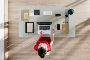 top view of a woman sitting at tidy desk and working on her laptop